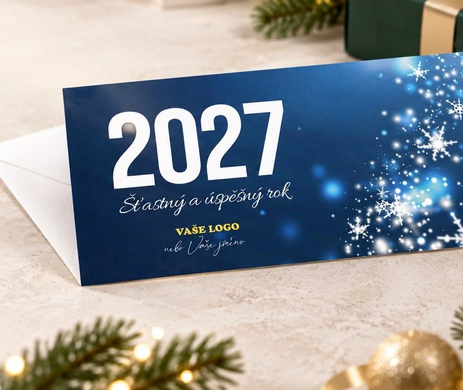 Vytištěná novoročenka 2027 na stole mezi vánočními ozdobami