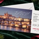 Sváteční Pražský hrad s Karlovým mostem v popředí – novoročenka s obálkou při pohledu shora.