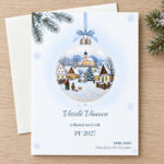 Novoročenka 630 – Zasněžená náves – PF 2027, vánoční koule se zasněženou návsí, chalupami a kostelem, A6 na výšku, ilustrační zátiší